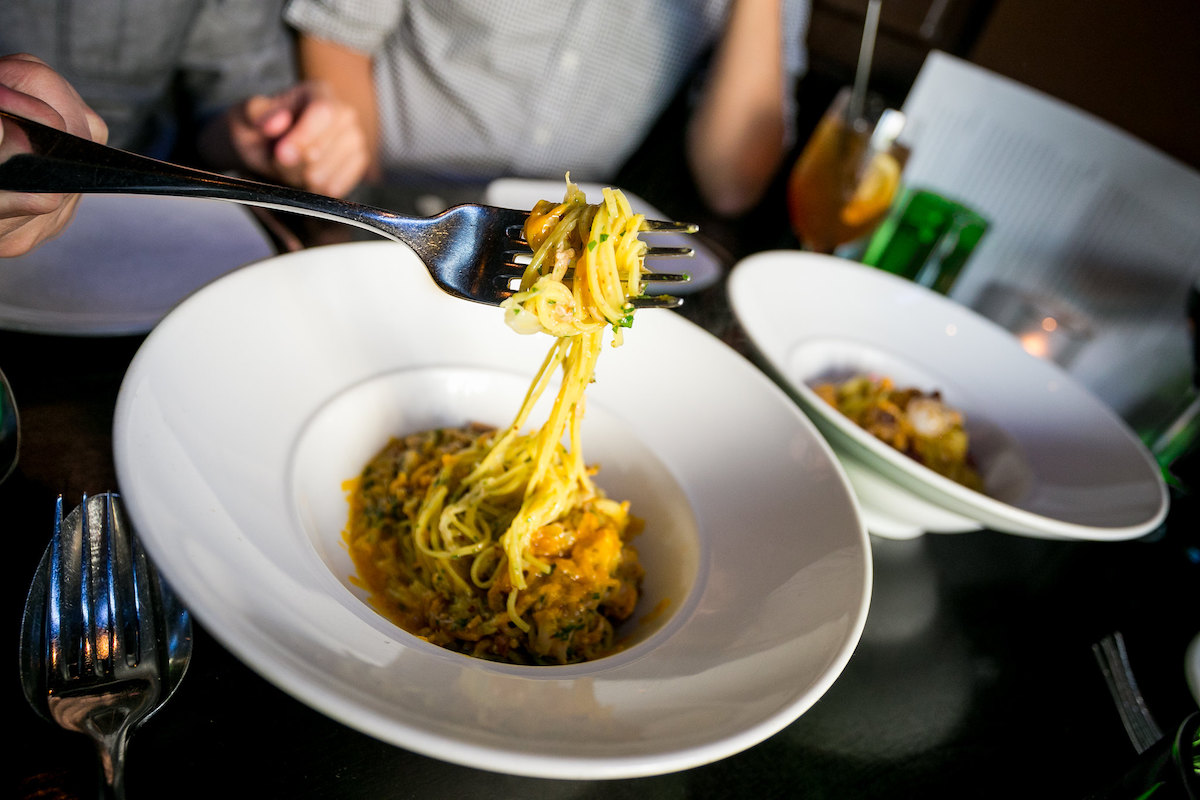 Alguien saca una pasta larga con un tenedor en SPQR, uno de los mejores restaurantes italianos de San Francisco.