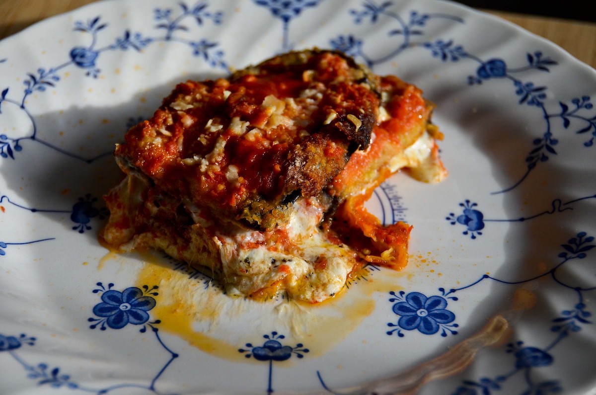 Primer plano de un plato azul y blanco con parmesano de berenjena vegetariano