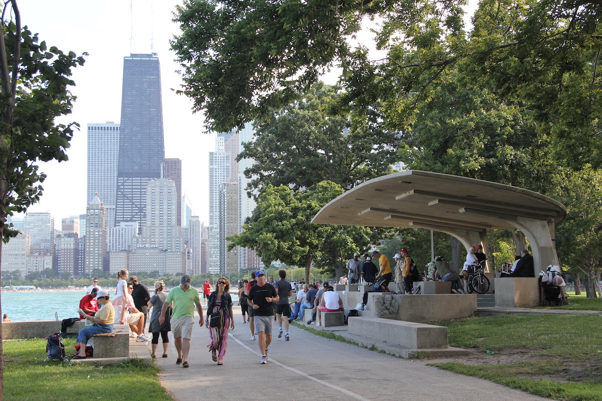 La gente trota, anda en bicicleta y se sienta y pasa el rato en el Lakefront Trail de Chicago con el horizonte de fondo