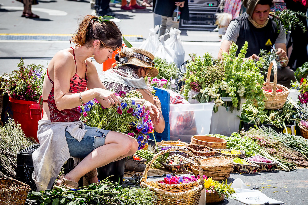 una mujer arregla flores frescas en un mercado callejero