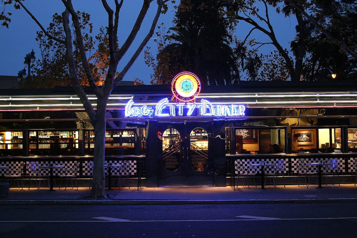 tiro fuera del restaurante de la ciudad de niebla en la noche. El cielo está oscuro y el letrero de neón brillante dice "Fog City Diner"