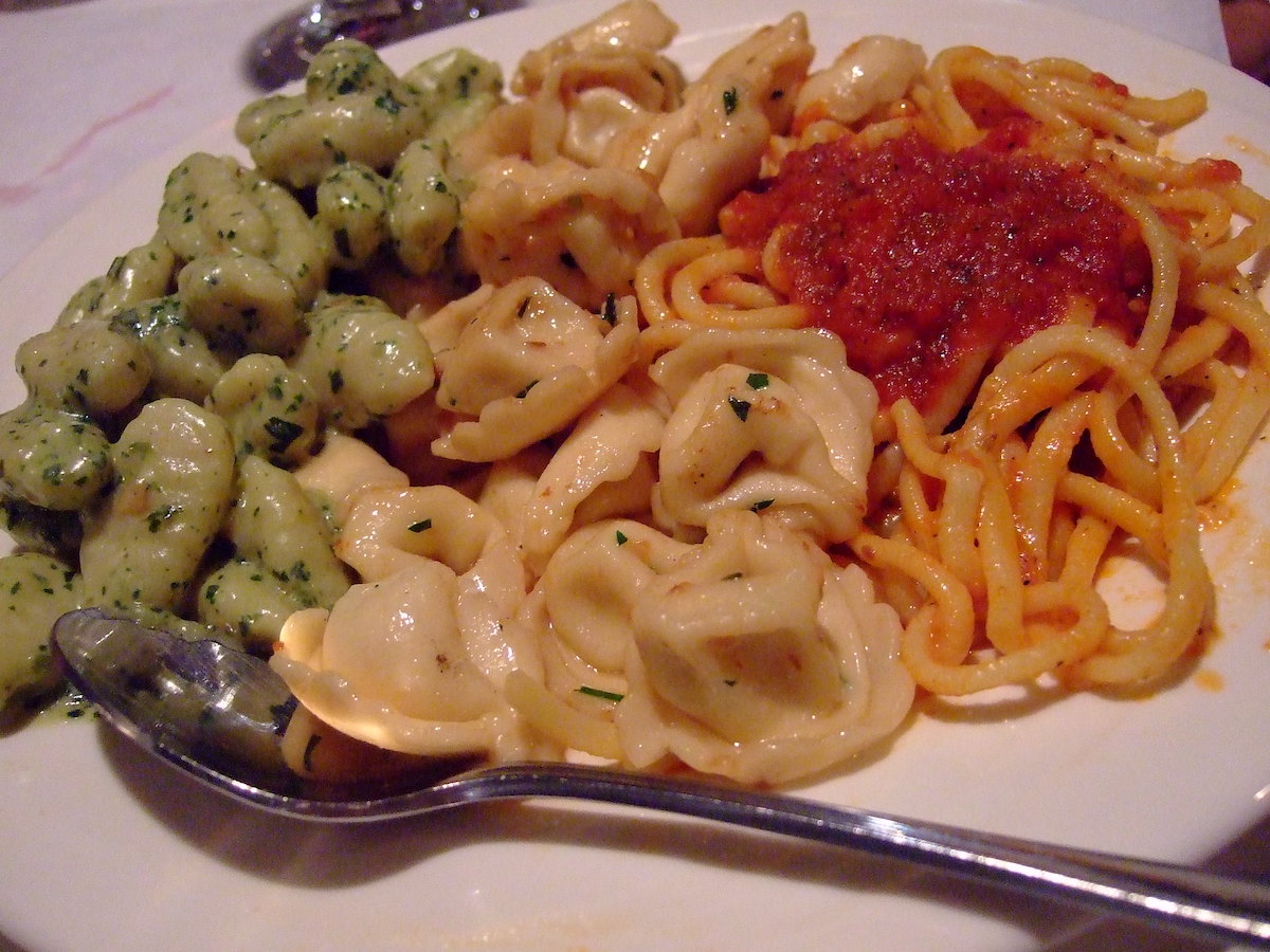 Primer plano de un plato de pasta de Lucia Ristorante, un restaurante de North End Boston, con tres tipos de pasta uno al lado del otro en un plato, lo que sugiere el verde, el blanco y el rojo de la bandera italiana.