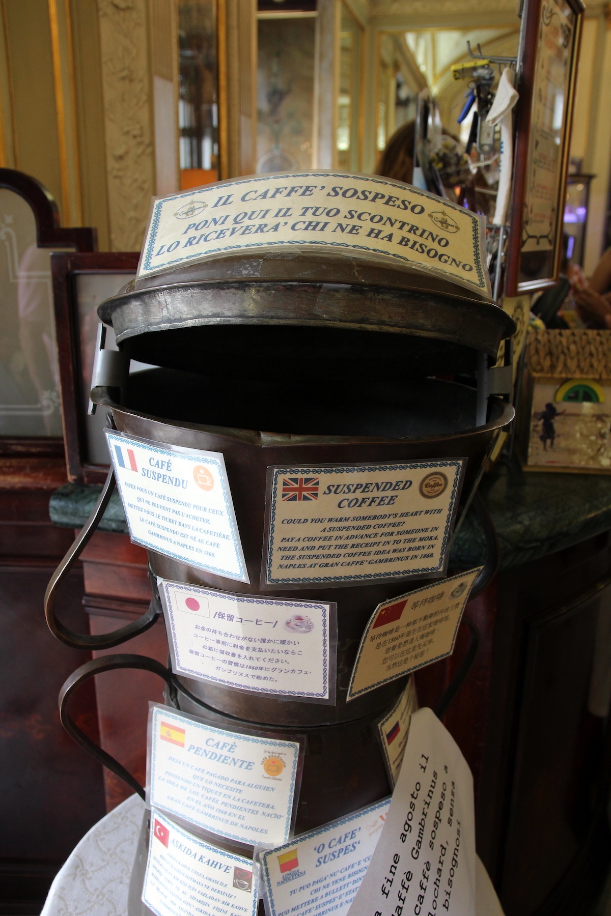 Una vieja cafetera está cubierta con tarjetas de "café sospeso", una tradición en la que un cliente de la cafetería puede comprar café extra y dejar un recibo para que alguien con mala suerte pueda venir y disfrutar de un café gratis.