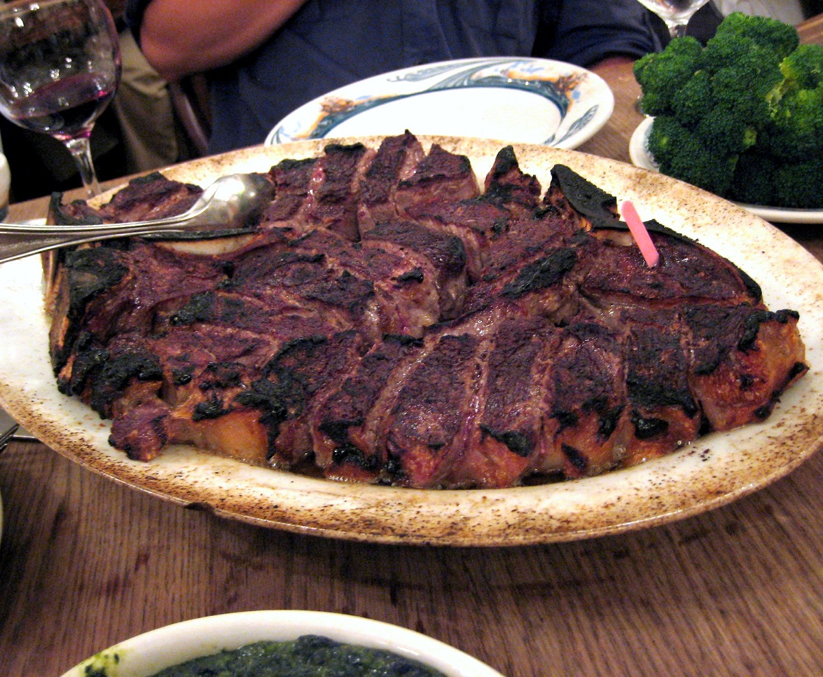 Un enorme plato de carne asada y carbonizada en un bol sobre una mesa de madera