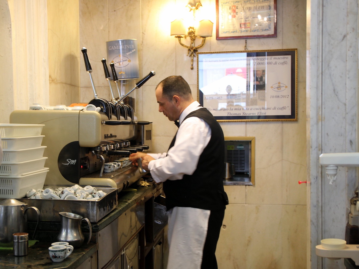 Un barista en Gran Caffe Cambrinus en Nápoles prepara espresso con una gran máquina de espresso.
