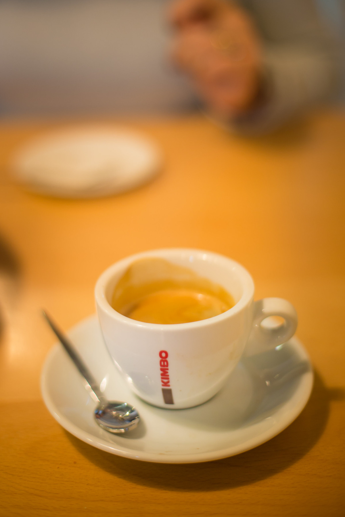 primer plano de una pequeña taza de espresso blanca con letras en el lateral que dicen "Kimbo", un popular tueste de café que se encuentra en Nápoles