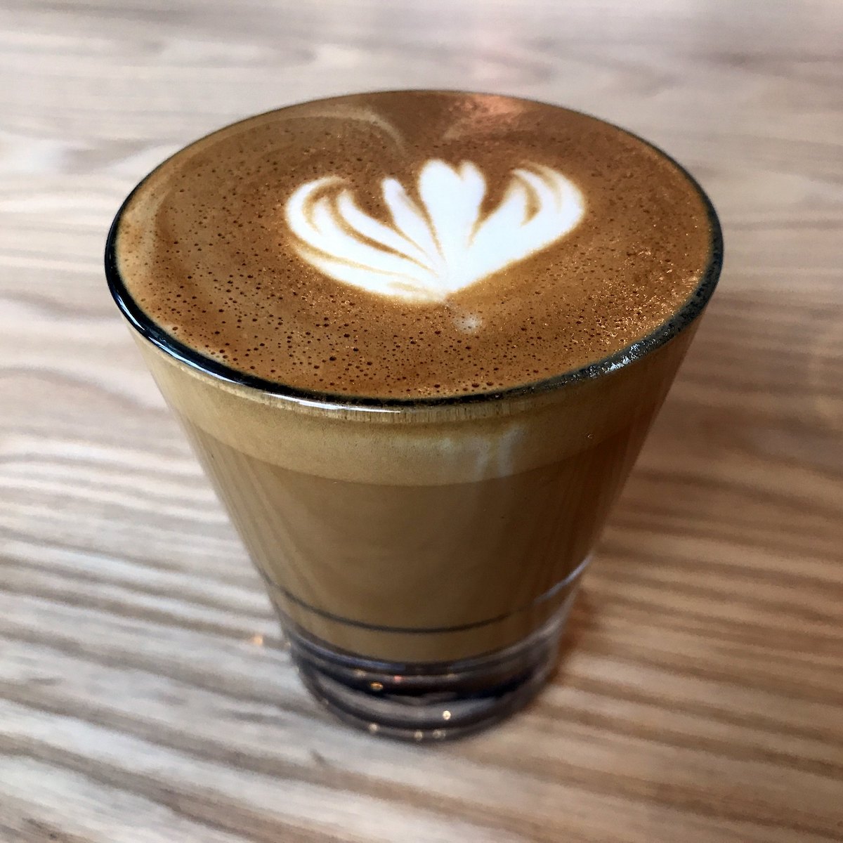 Primer plano de arte latte en una bebida de café muy pequeña en un vaso transparente