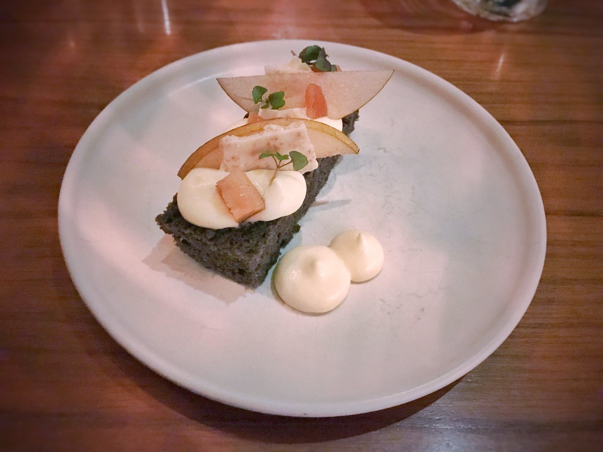 Cierra un plato en el restaurante Michel-star en Mister Jiu's en San Francisco. Es un pastel de sésamo negro con mousse de jengibre, peras asadas y pera asiática.