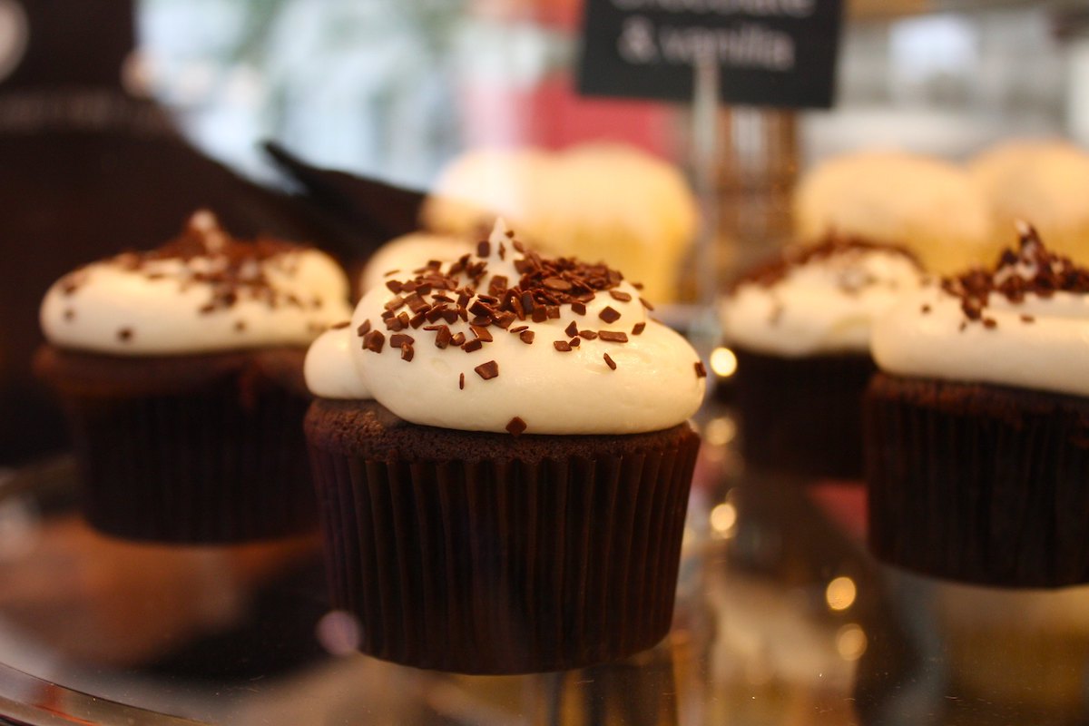 Cierre un plato de cupcakes de chocolate con glaseado blanco y espolvoreado con chispas de chocolate.