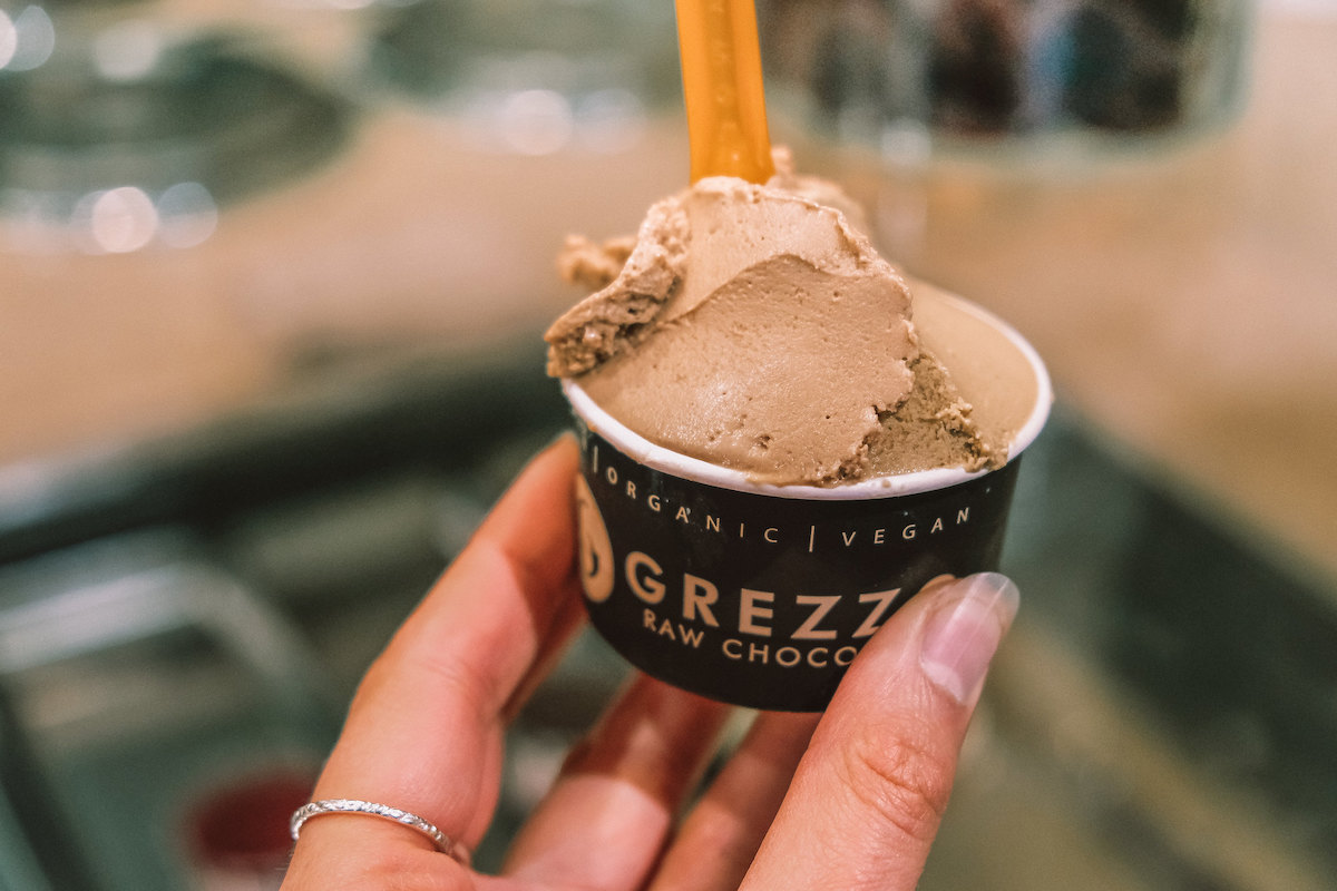 Cerca de alguien tomando una pequeña taza de helado de chocolate vegano