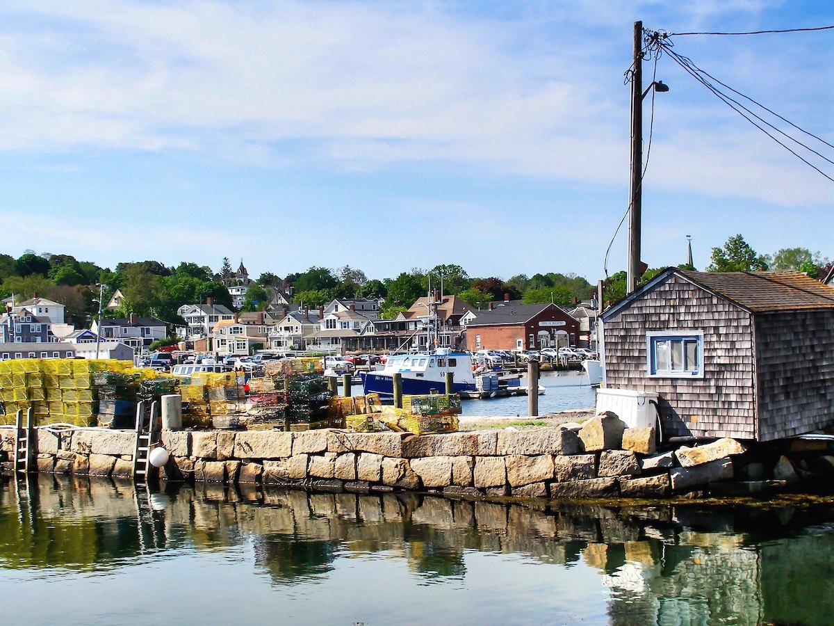 Las cajas se apilan en un muelle cerca del agua de un puerto en Rockport, Massachusetts. Los barcos flotan en el fondo