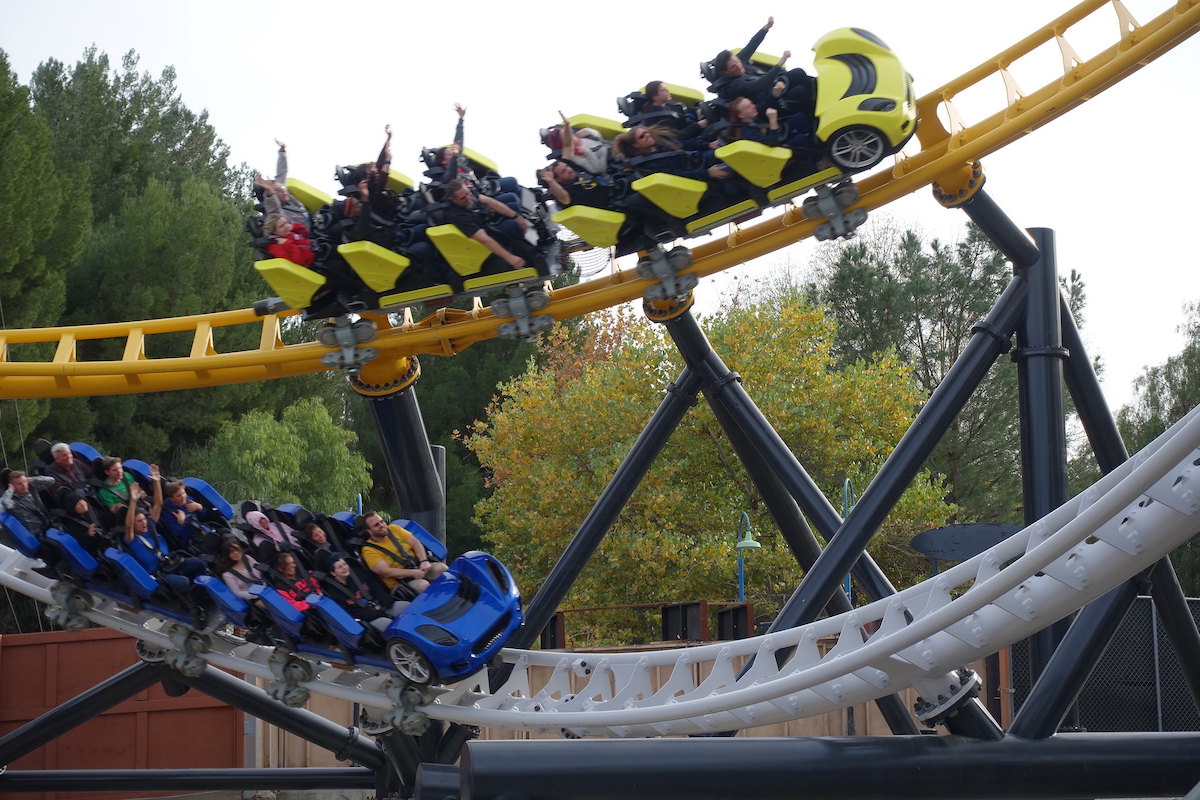 Dos vagones de montaña rusa en primer plano bajan por una montaña rusa en Six Flags Magic Mountain, una parada divertida en un viaje por carretera de Los Ángeles a San Francisco
