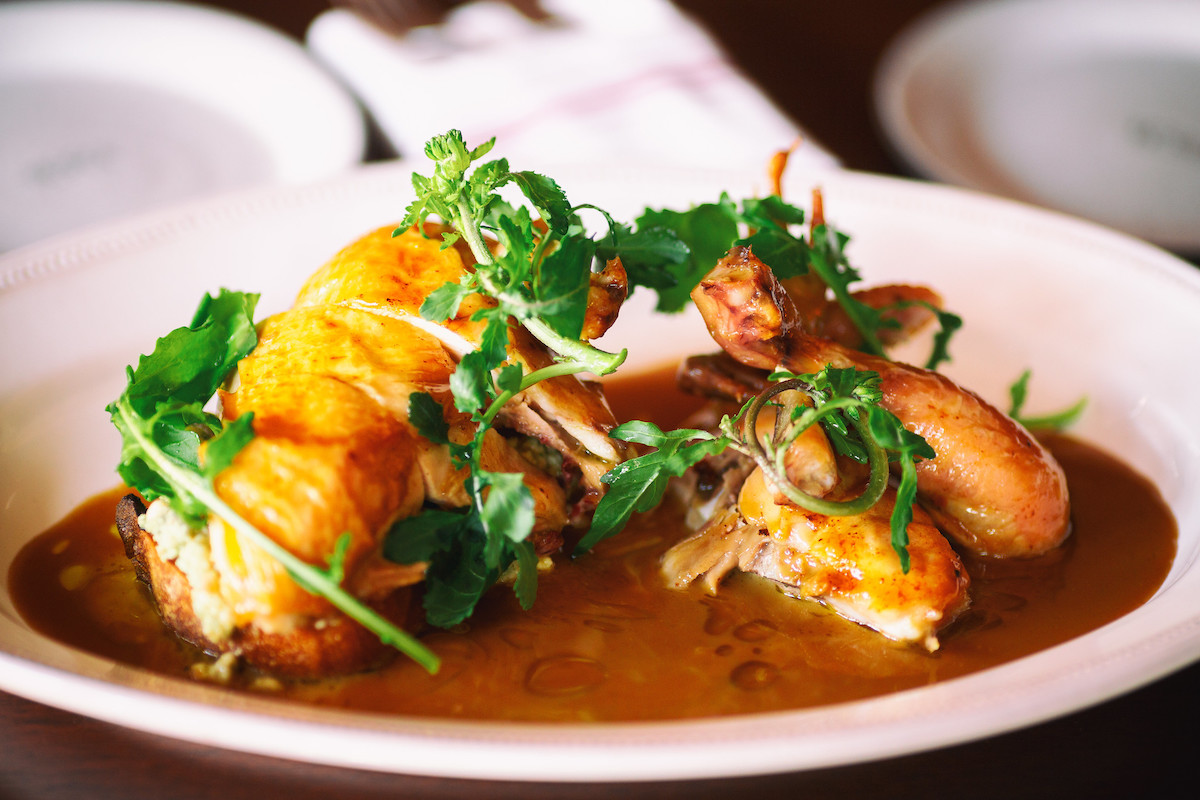 primer plano de un plato blanco con pollo asado y salsa marsala