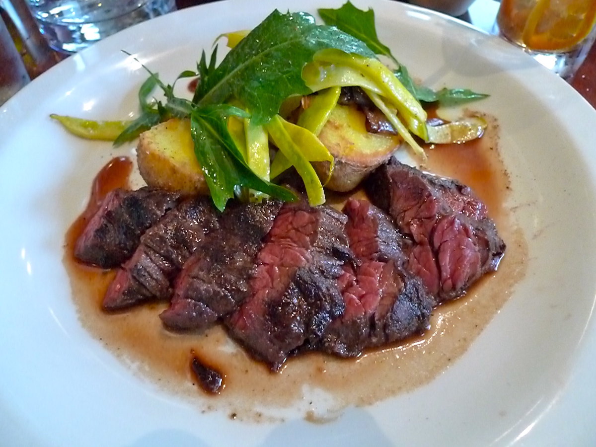 Cierra un plato de bistec a la parrilla con ensalada en Nopa, un popular restaurante de San Francisco