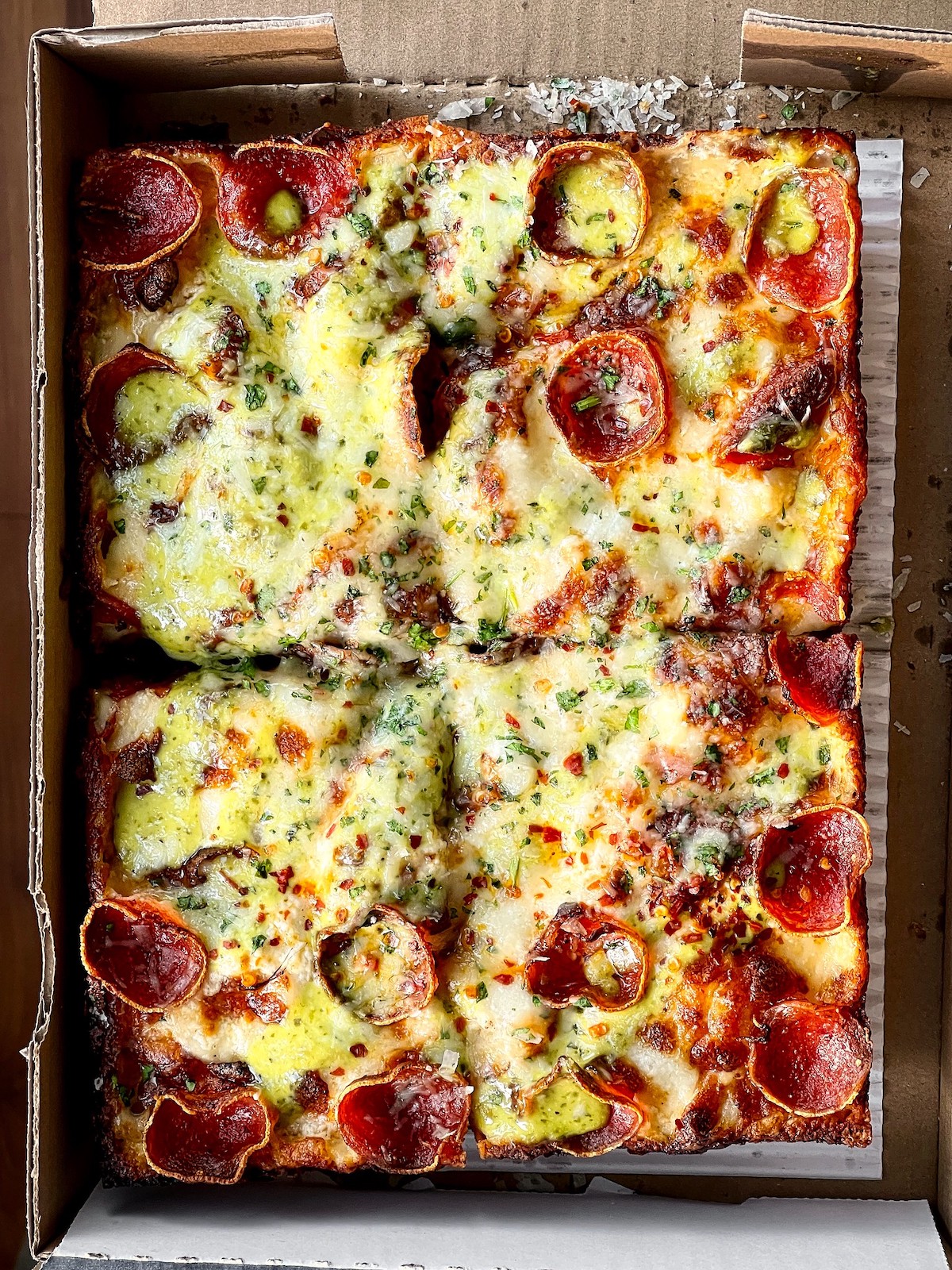 Primer plano de una pizza rectangular de Square Pie Buys en San Francisco. La rebanada está cubierta con pepperoni y mucho queso derretido.