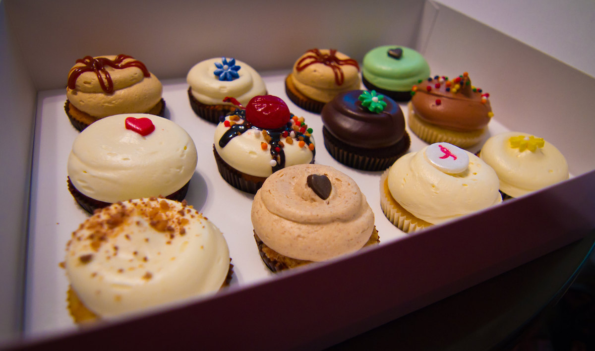 Cierra la caja de una docena de cupcakes de Georgetown Cupcakes. ¡Todos los cupcakes están bellamente decorados y se ven demasiado buenos para comerlos!