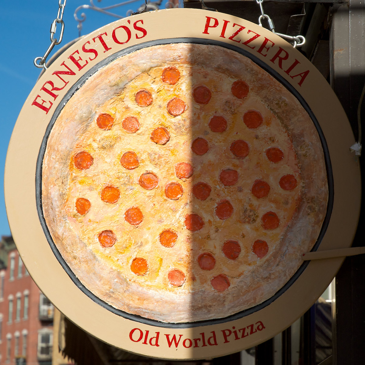 Cartel redondo con una imagen grande de una pizza de pepperoni y el nombre "Juego Pizzería Ernesto en línea" en letras rojas. Ernesto's es un popular restaurante de North End Boston.