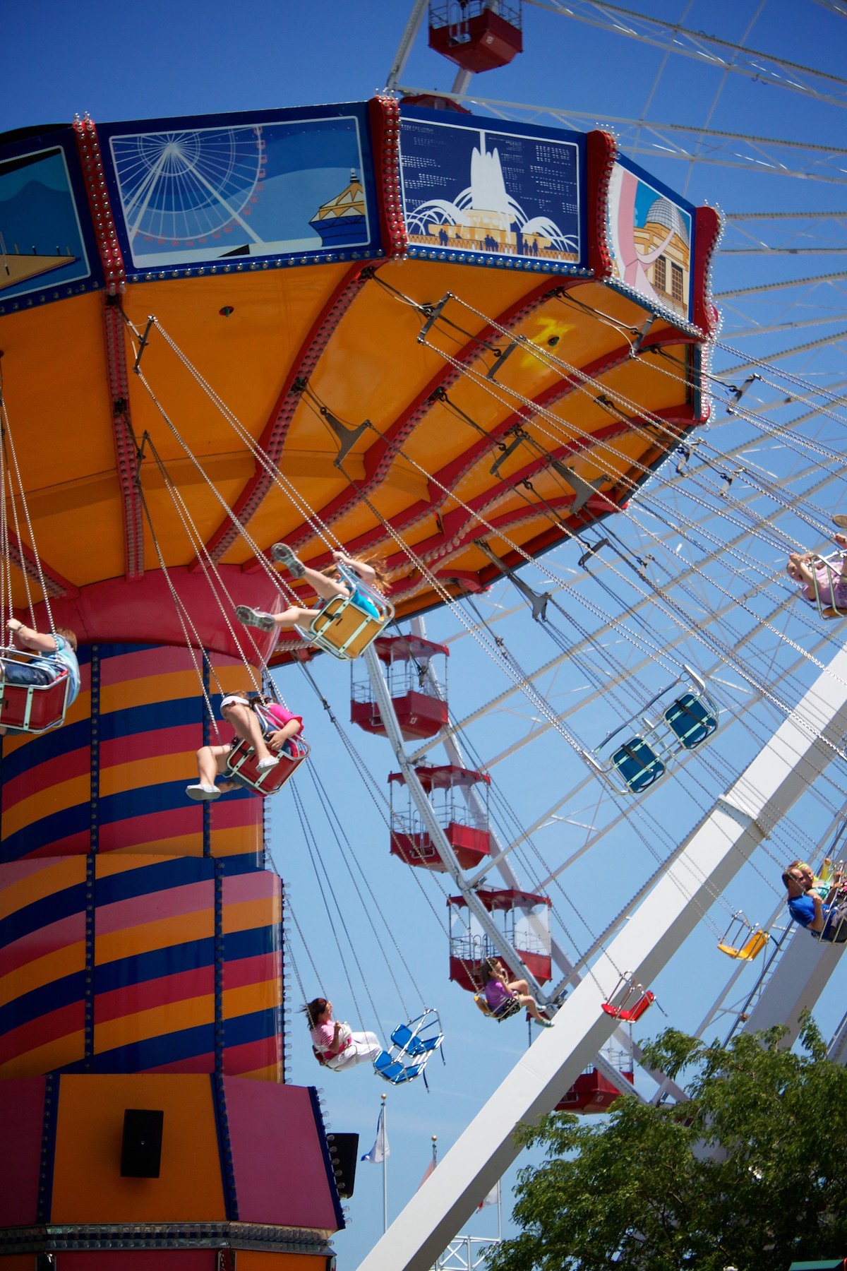 la gente va en un colorido paseo en columpio con una gran rueda de la fortuna de fondo en el Navy Pier de Chicago, un gran lugar para ir con niños