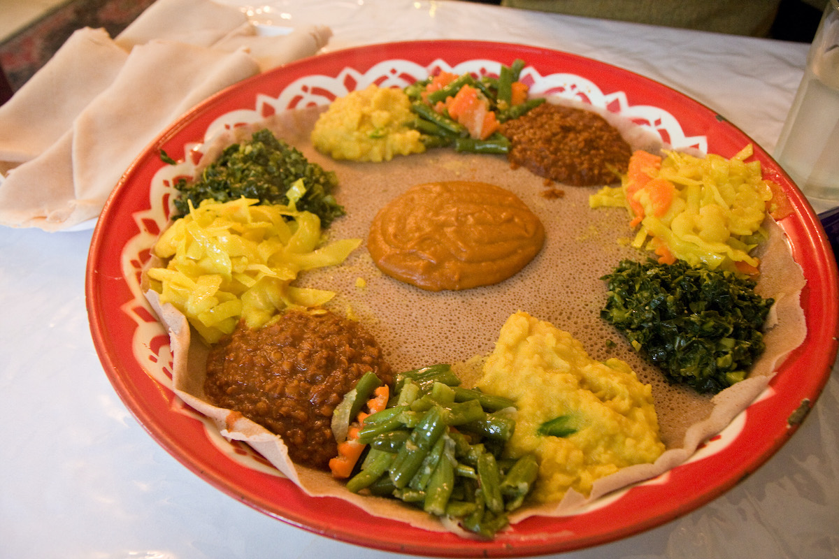 Un plato para compartir de comida vegetariana etíope con verduras y salsas sobre pan esponjoso