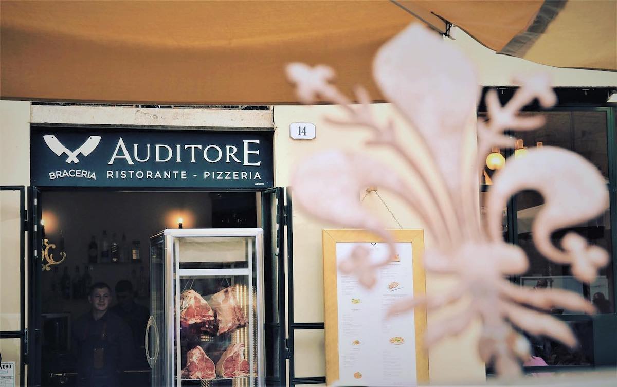 Afuera de un restaurante con un cartel encima de la puerta que dice Auditore Ristorante Braceria