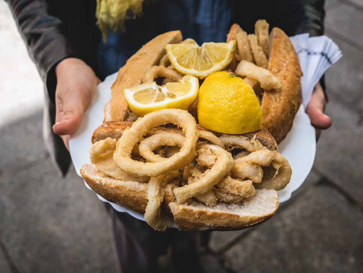 Una bandeja de sándwiches de calamares fritos en rollos de baguette con gajos de limón.