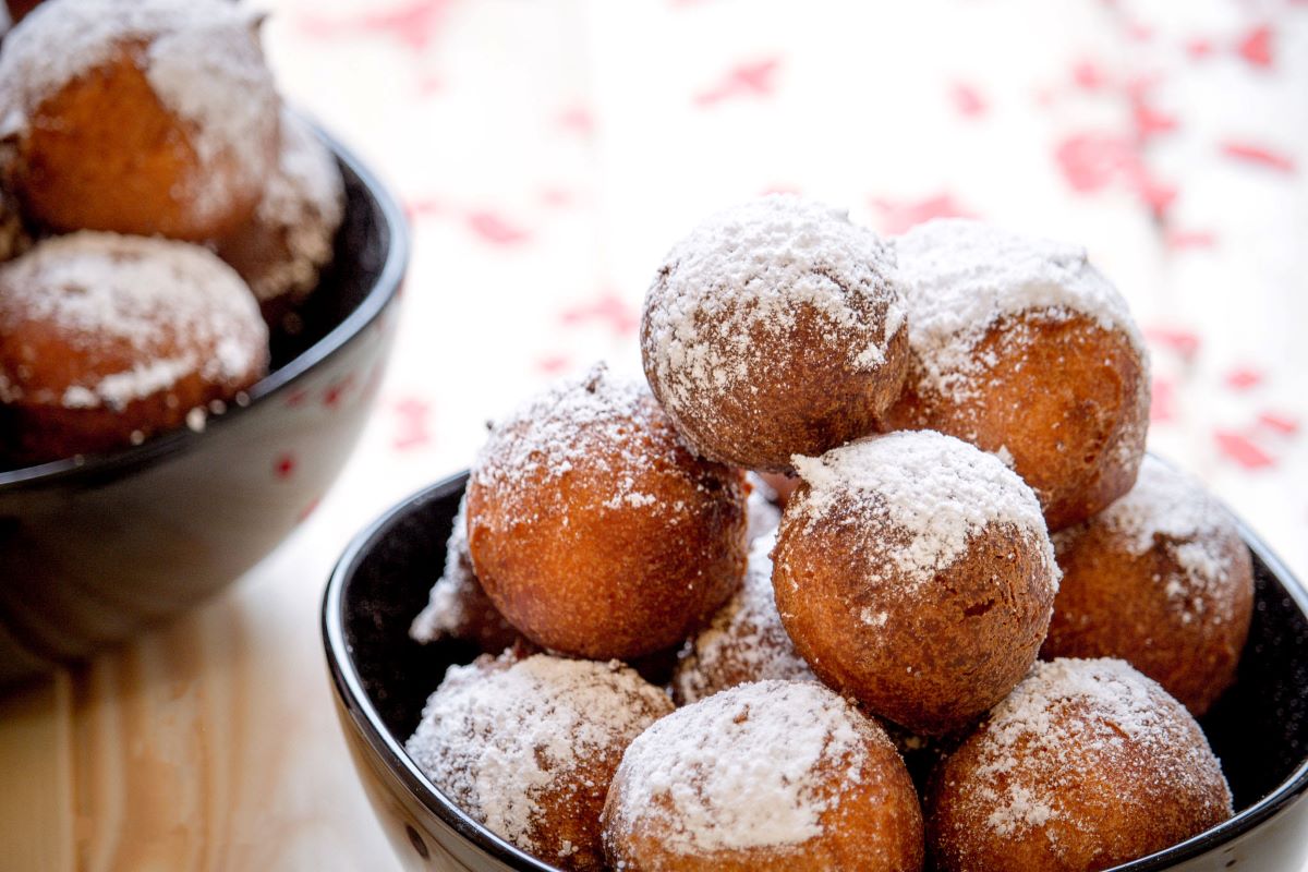 bolas de masa frita con azúcar en polvo en un tazón negro