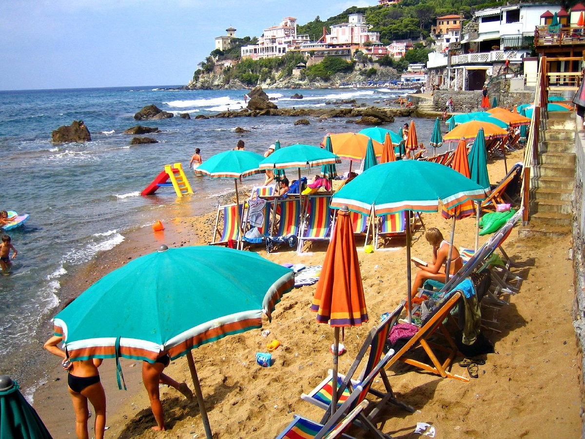 Bañistas y nadadores llegan a una pequeña playa con una montaña al fondo