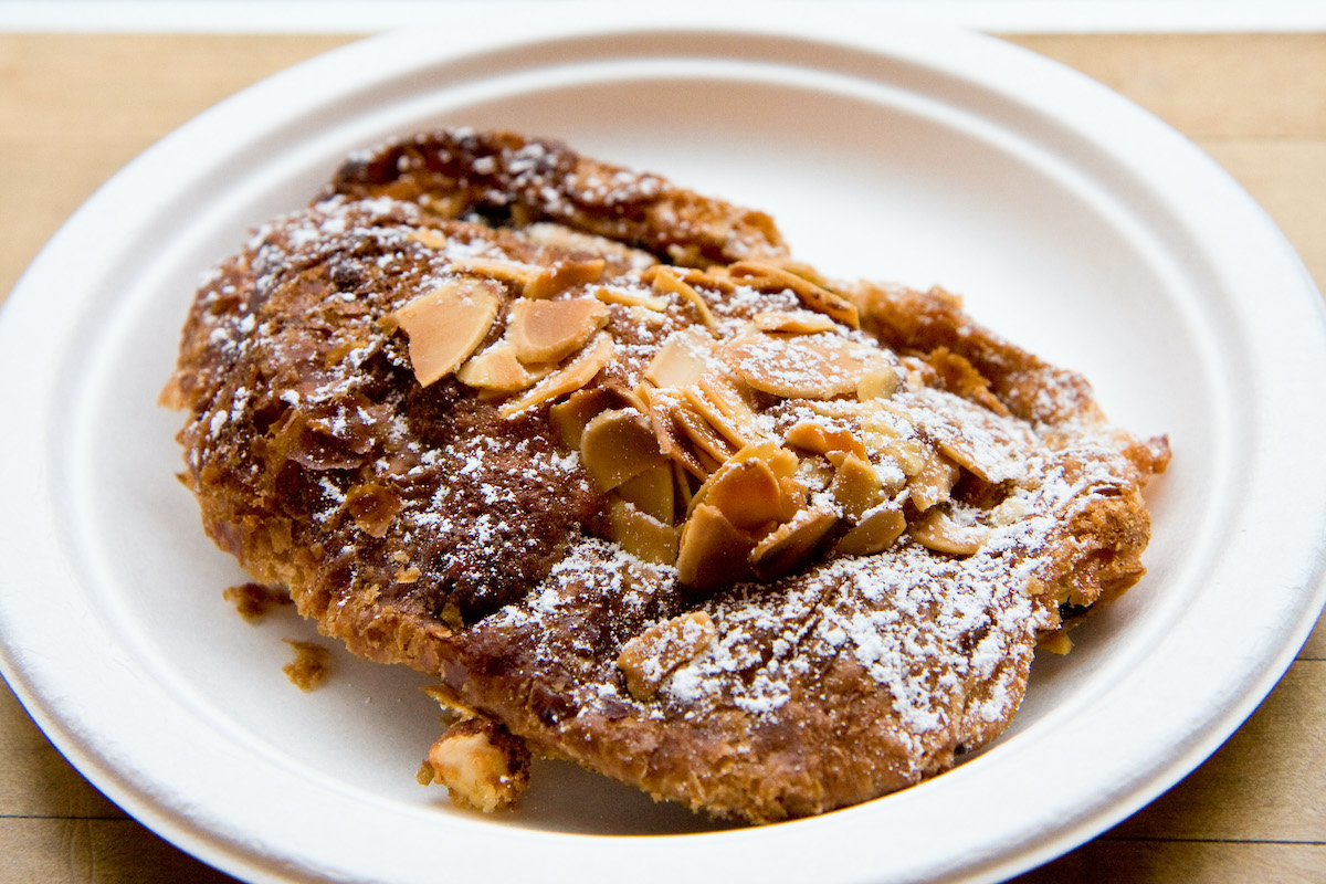 croissant de chocolate con almendras en un plato blanco