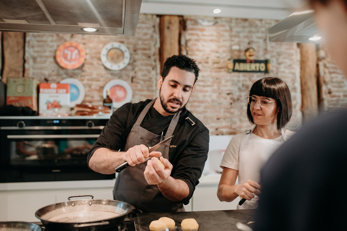 Un estudiante en la clase de cocina observa cómo un chef demuestra cómo hacer algo en la cocina.