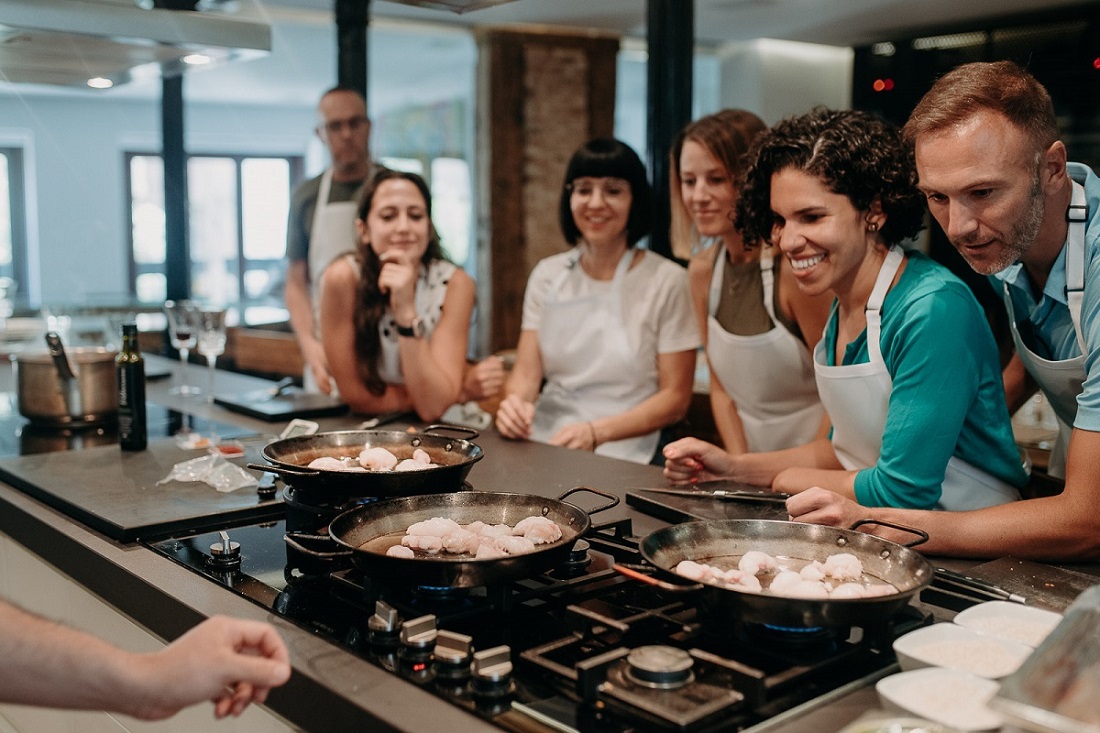 Los estudiantes en la clase de cocina de Devour miran sus paellas en la estufa