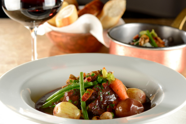 Plato boeuf bourguignon con vino tinto al lado