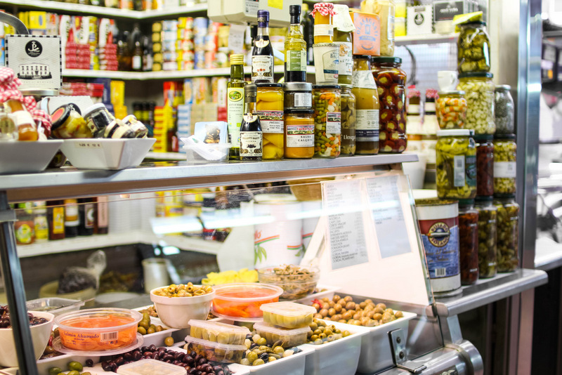 Los mercados de alimentos de Barcelona son una experiencia sensorial y conmovedora, con puestos como este que venden de todo, ¡desde aceitunas hasta converves y queso! ¡Echa un vistazo a estos mercados poco conocidos en Barcelona y prueba algunas de nuestras recomendaciones para sabrosos bocados!