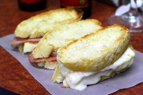 Ver el queso de cabrales derretirse sobre finas lonchas de cerdo y sentarse sobre un delicioso pan recién hecho nos da hambre, uno de los mejores bocadillos de Sevilla.