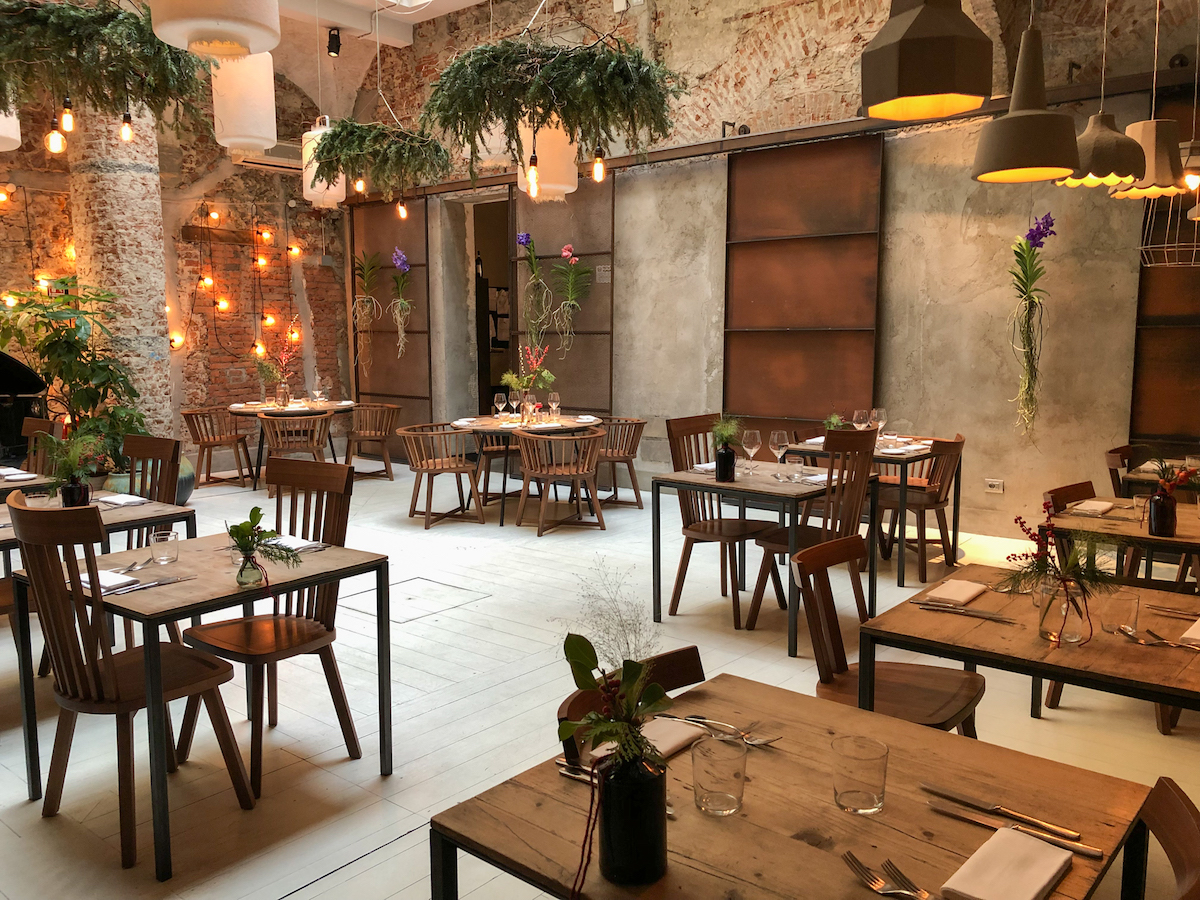 Comedor con mesas y sillas rústicas de madera decoradas con plantas