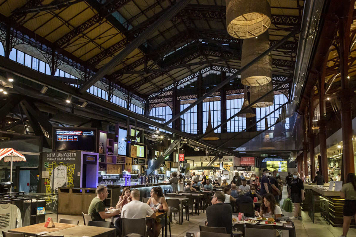 Dentro de un gran mercado interior de alimentos con varios puestos de restaurantes