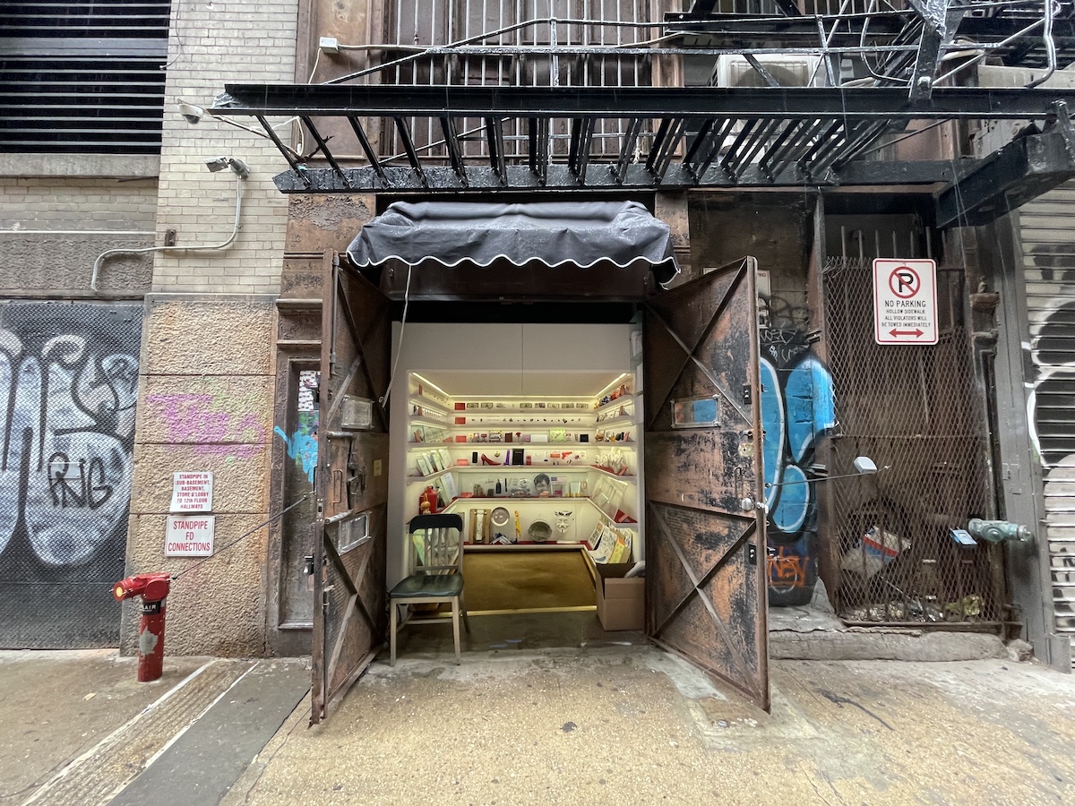 Viejas puertas del hueco del ascensor que se abren a un camino urbano para revelar estantes con varios objetos en el interior