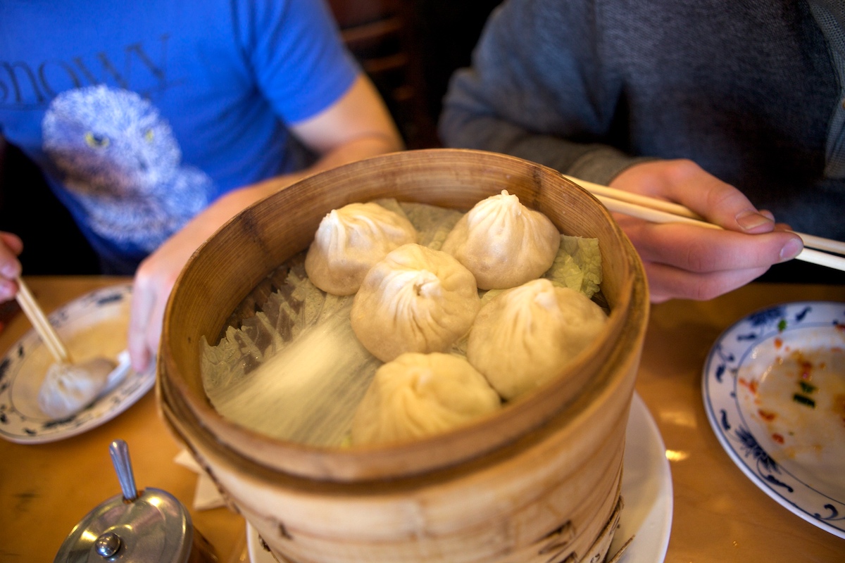Cinco albóndigas de sopa china en una cesta redonda de madera.