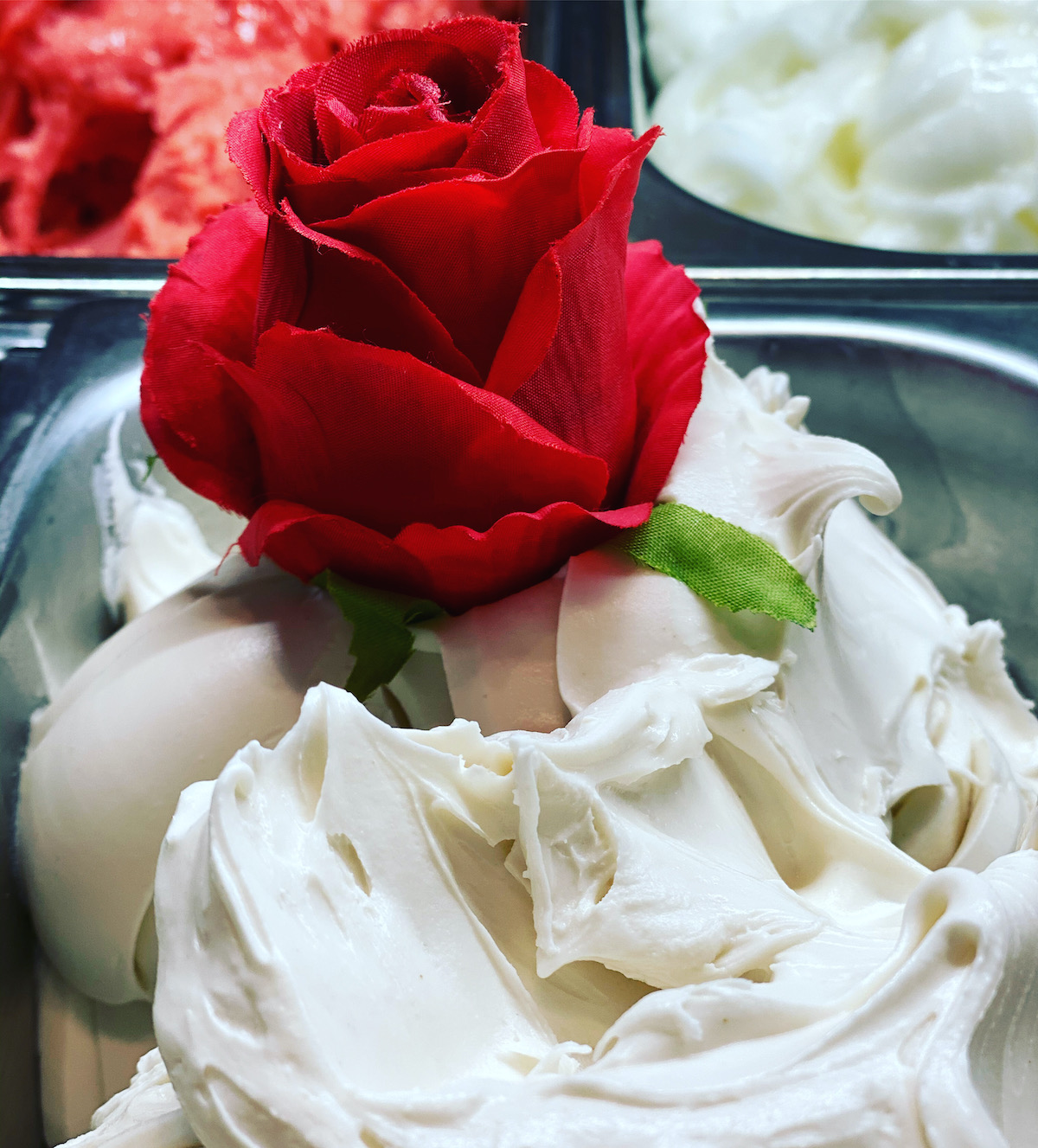 Gelato blanco en exhibición en una tienda decorada con una rosa roja