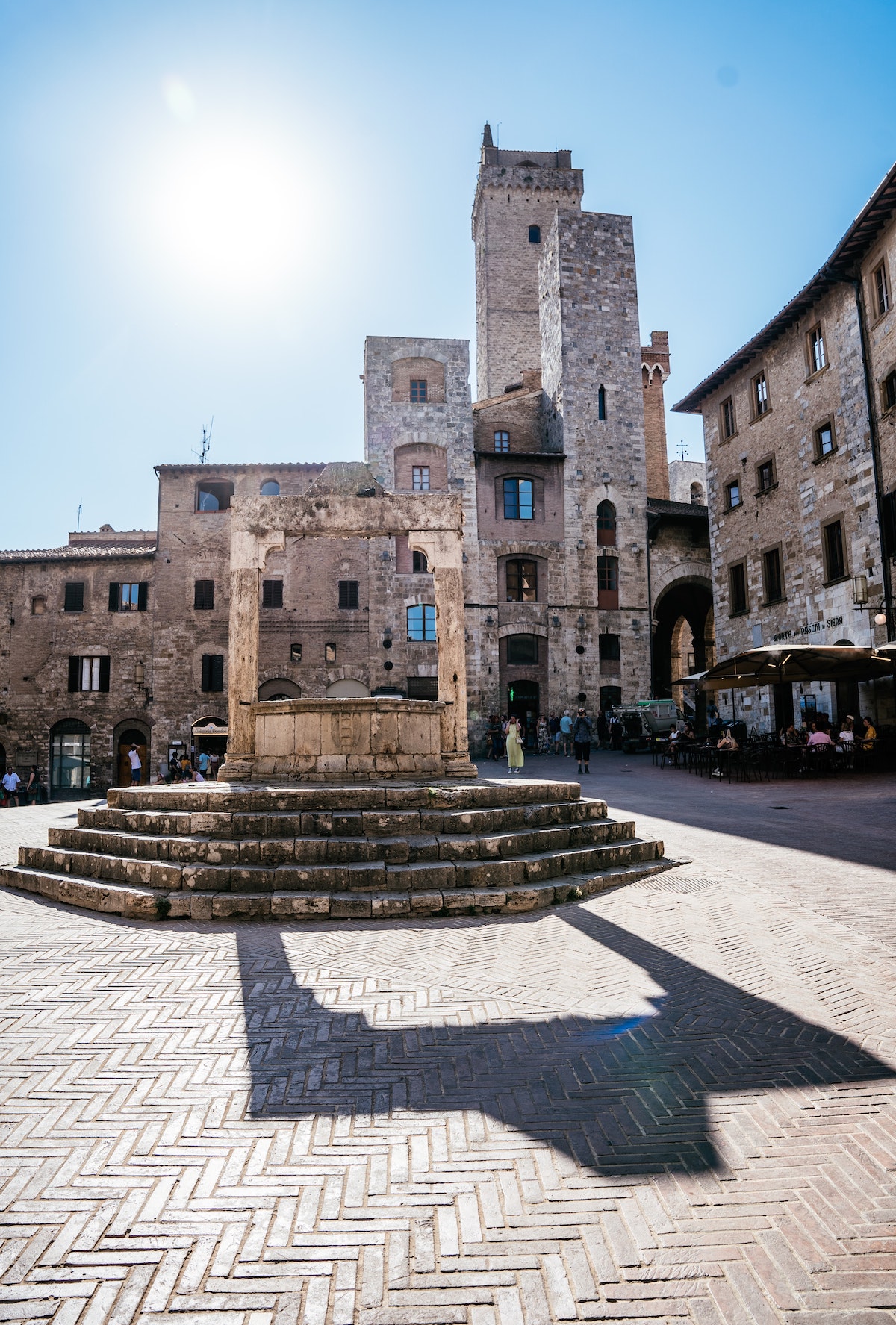 La plaza de la ciudad medieval de San Gimignano con una gran fuente de piedra en el centro.