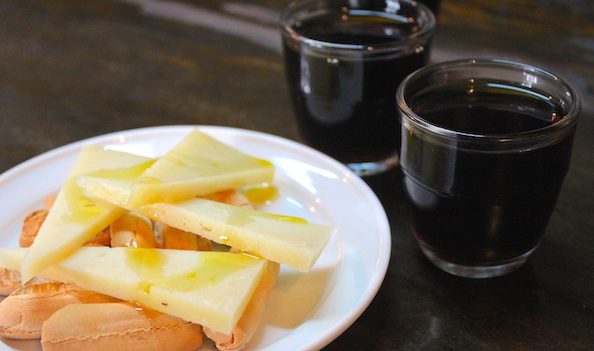 Vino de naranja y queso en Taberna Peregil. Uno de nuestros mejores consejos de viaje para Sevilla es qué comen los lugareños y cuándo lo comen. 