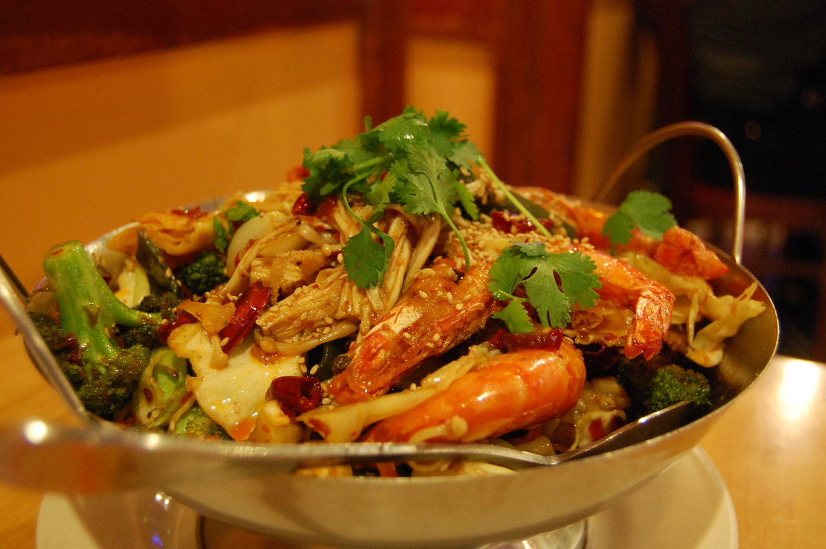 Un plato chino a base de mariscos y vegetales servido en un tazón de metal