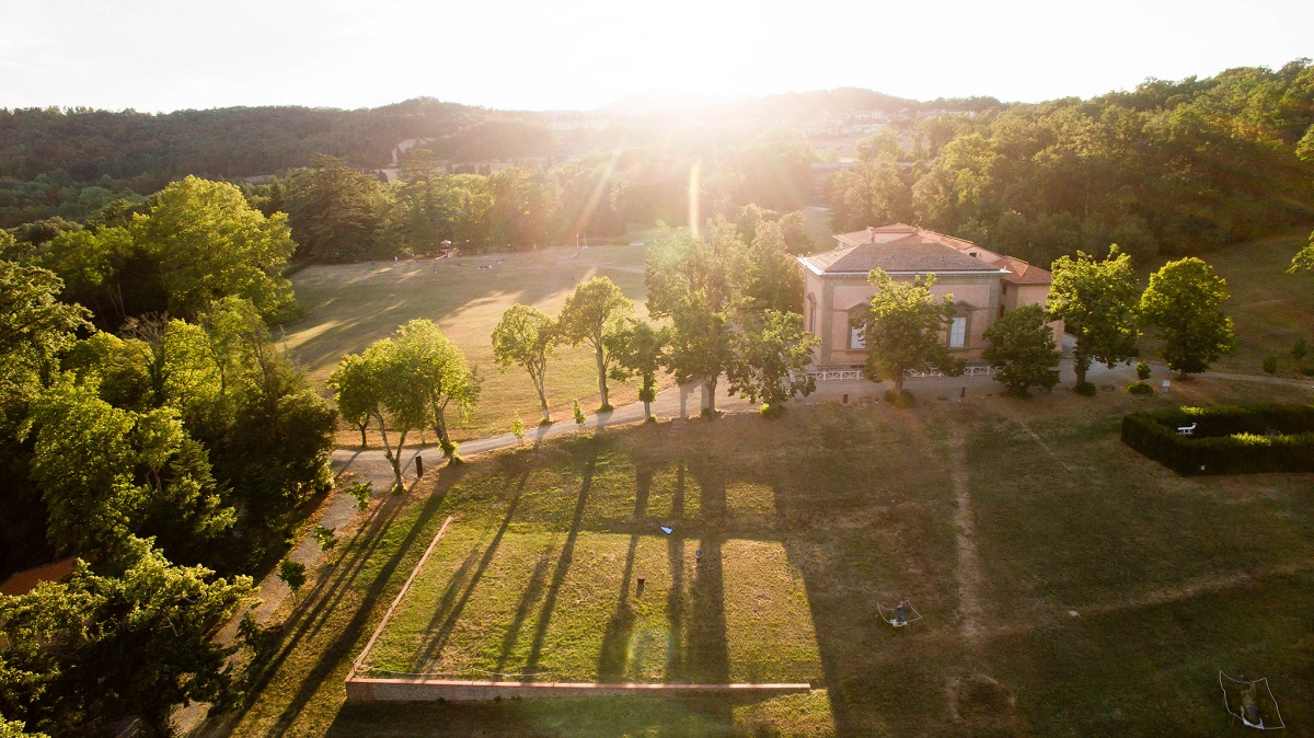 Sol cayendo sobre una villa en la Toscana con muchos árboles y largas sombras