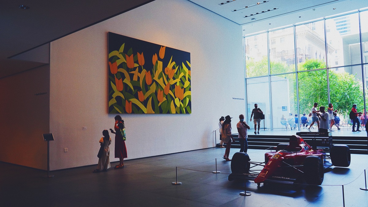 Los visitantes de una galería de arte miran una gran pintura en una pared.