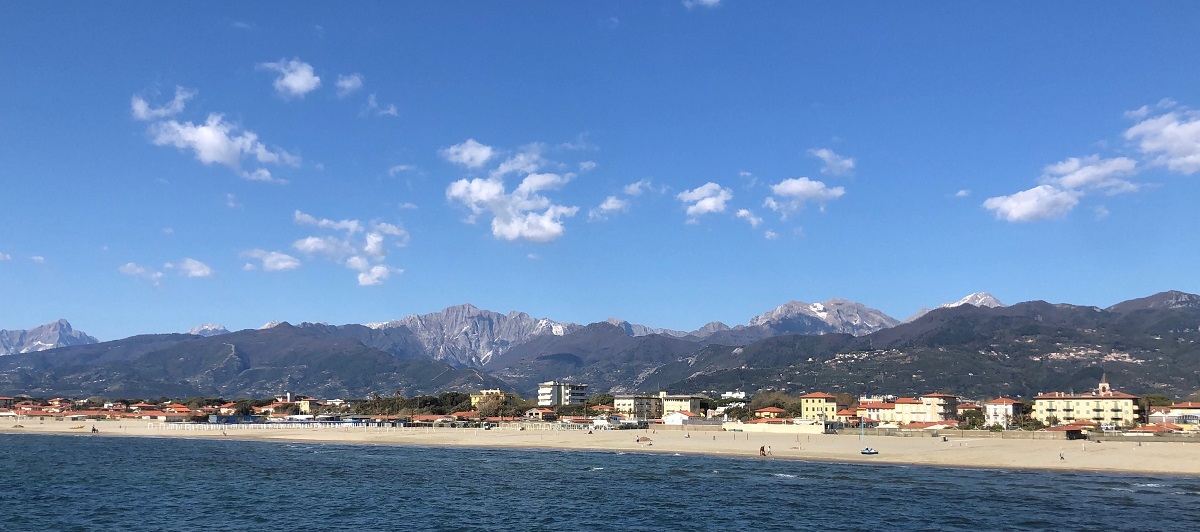 Una larga playa de arena blanca con montañas al fondo