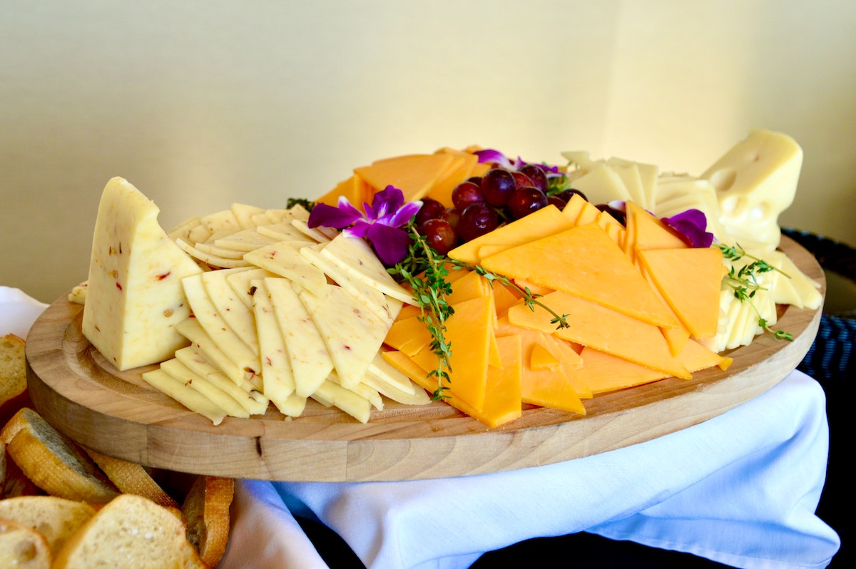 Mezcla de queso adornada con flores y hierbas comestibles sobre una tabla de madera