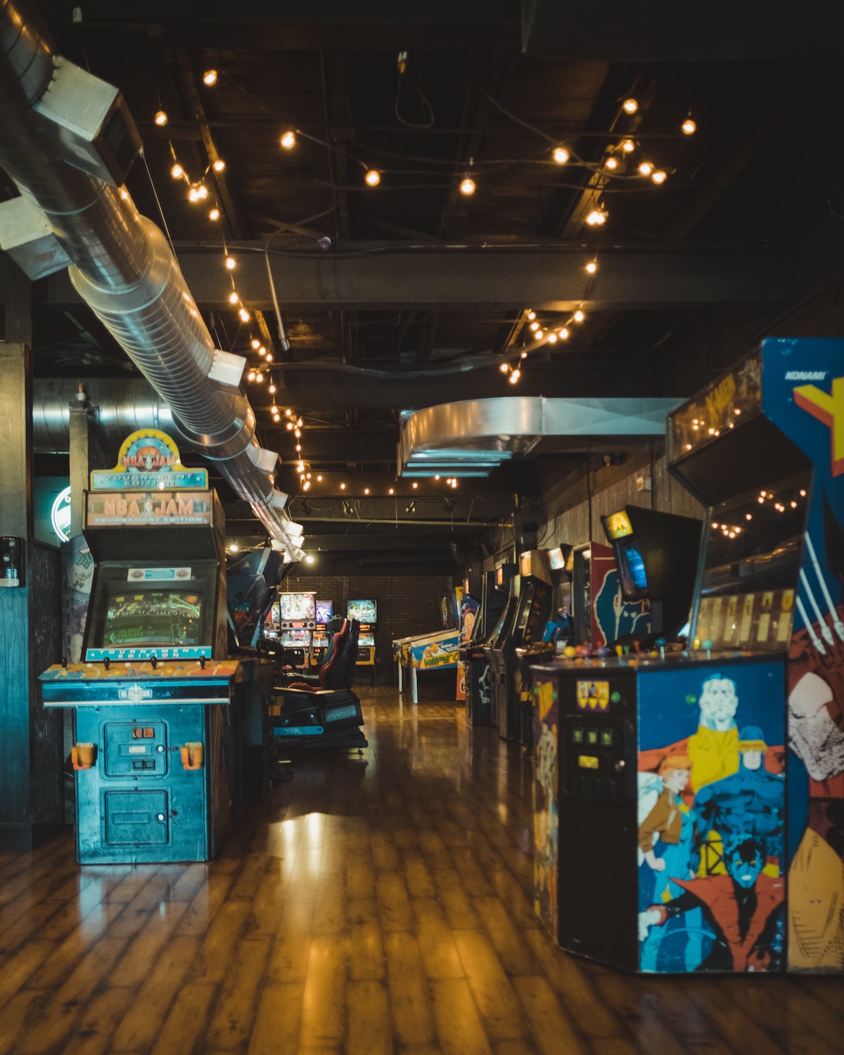 Dentro de una sala de juegos con máquinas de videojuegos retro y luces de cuerda