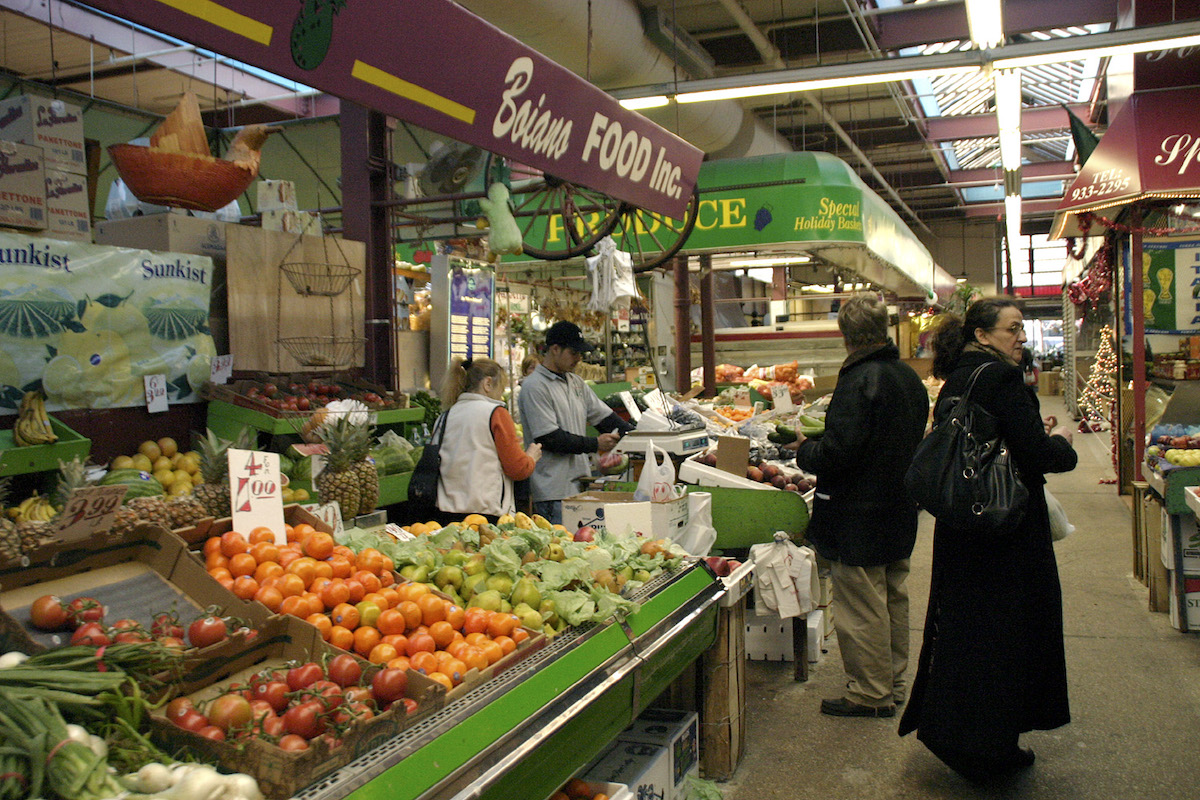 Personas de pie cerca de un puesto de productos frescos en un mercado