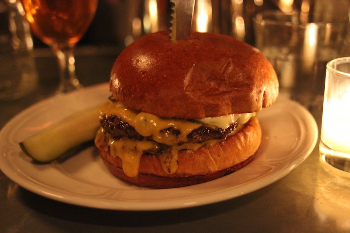Hamburguesa con queso y pepinillos en un plato blanco