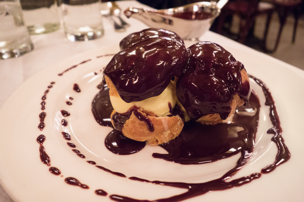 Profiteroles cubiertos con salsa de chocolate en un plato blanco