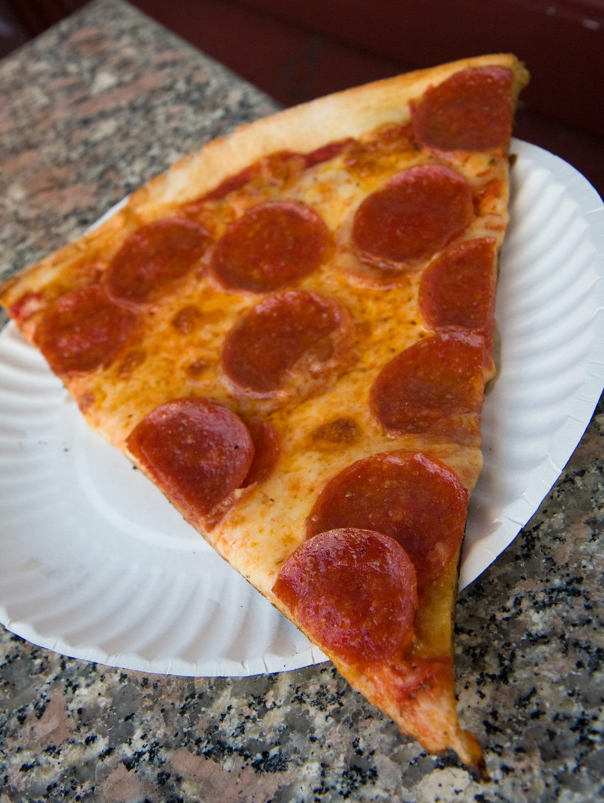 Corta la pizza de pepperoni en un plato de papel
